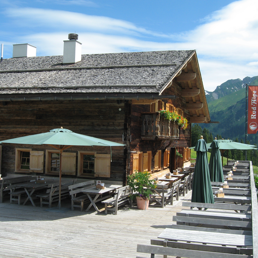 A wooden hut with a terrace and sun umbrellas on Kriegerhorn family mountain.