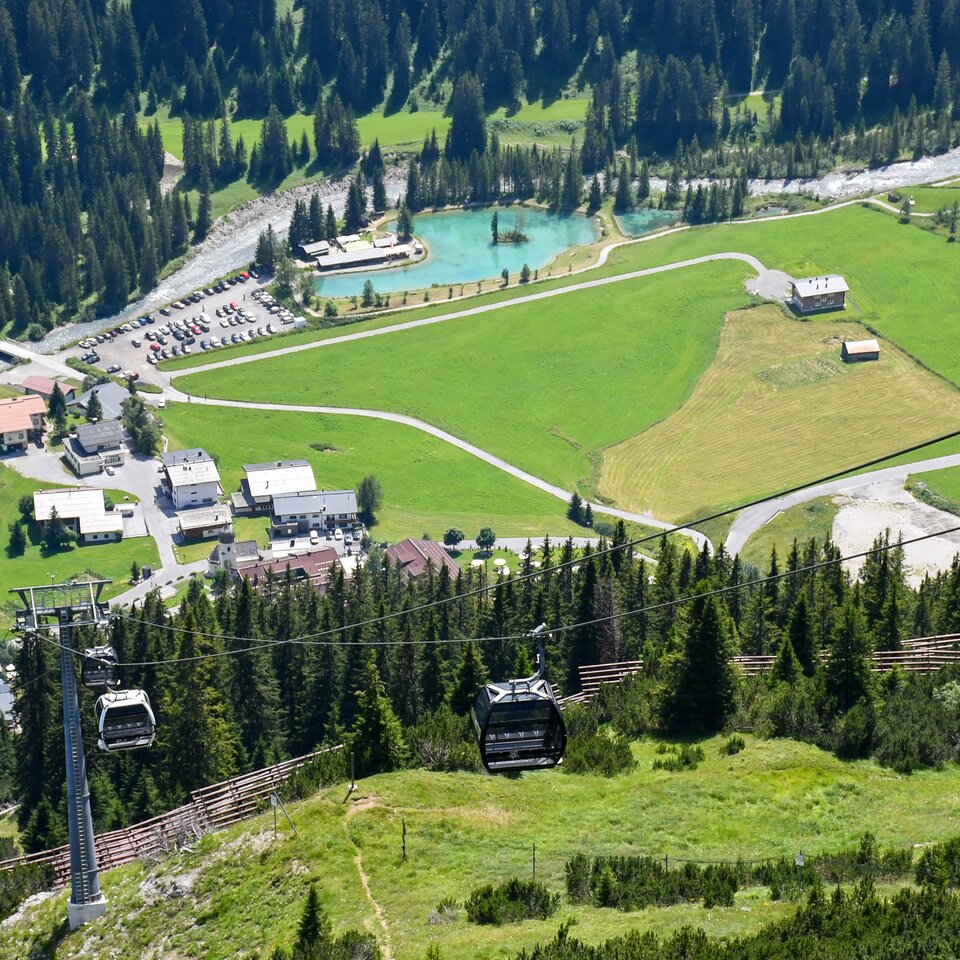Cable car over green fields and buildings on Kriegerhorn family mountain.
