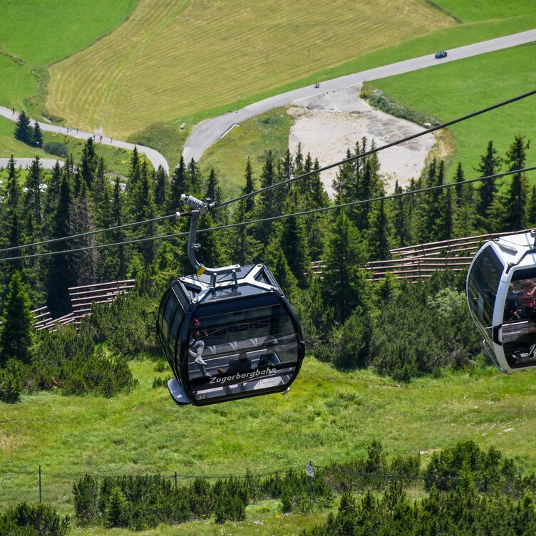 Two Zugerbergbahn cabins above a green landscape.