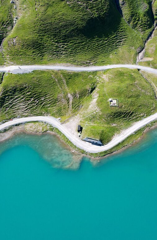 Luftaufnahme vom Zürsersee, der in türkiser Farbe in der Sonne scheint am Naturberg Seekopf.