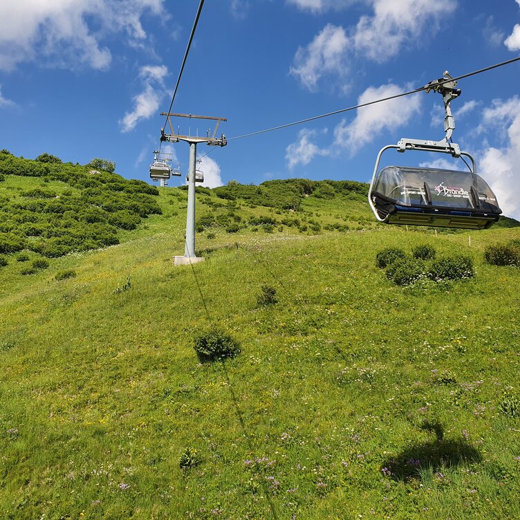 Cable car traveling over green meadows at Seekopf nature mountain.