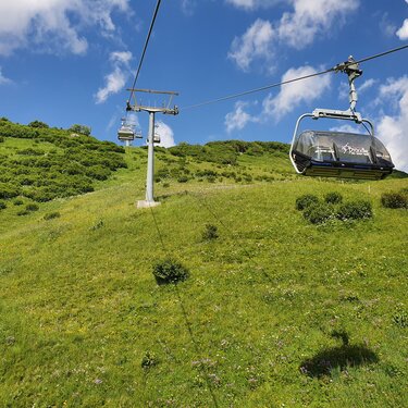 Cable car traveling over green meadows at Seekopf nature mountain.