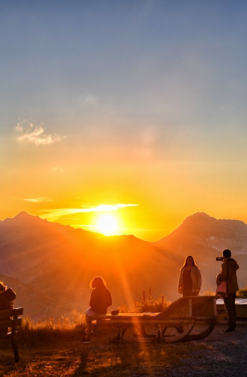 Menschen genießen einen Sonnenuntergang am Panoramaberg Rüfikopf.