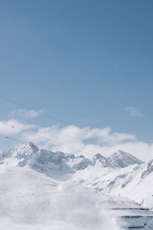 Winter mountain scene with cable car under blue sky.