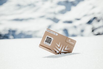 Golden gift card with QR code in the snow, against a mountain backdrop.