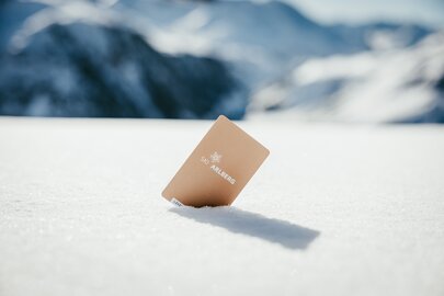 A ski pass labeled 'Ski Arlberg' is stuck in the snow.