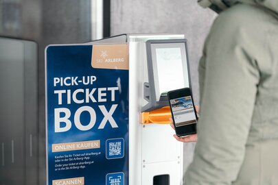 Person scanning a smartphone at a Ski Arlberg ticket machine.