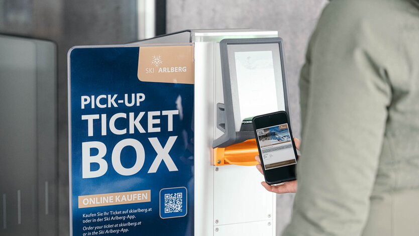 Person scanning a smartphone at a Ski Arlberg ticket machine.