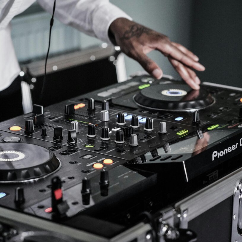 DJ operating a Pioneer mixer, close-up of hands.