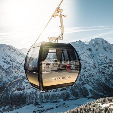 Moët & Chandon gondola soaring above snowy Alps.