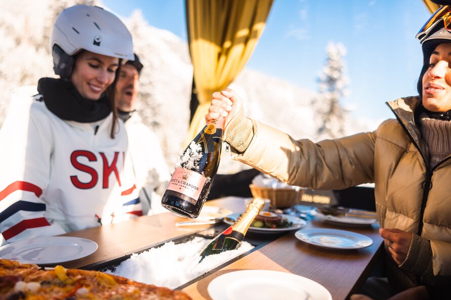 Skifahrer genießen Champagner in einer Gondel.