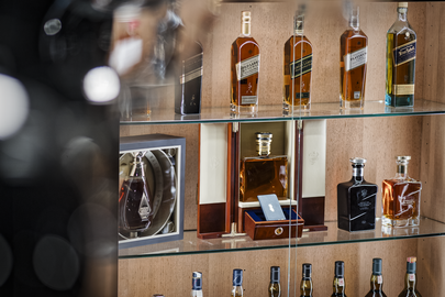 Ein Regal mit verschiedenen Whisky-Sorten, darunter Johnnie Walker und Noblige, sowie edlen Flaschen in dekorativer Anordnung.