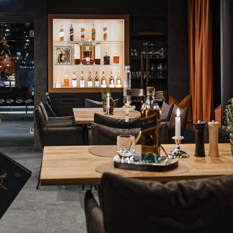 Elegante Lounge im Schlegelkopf Restaurant mit Whiskyflaschen im Regal und gemütlichen Sitzbereichen.