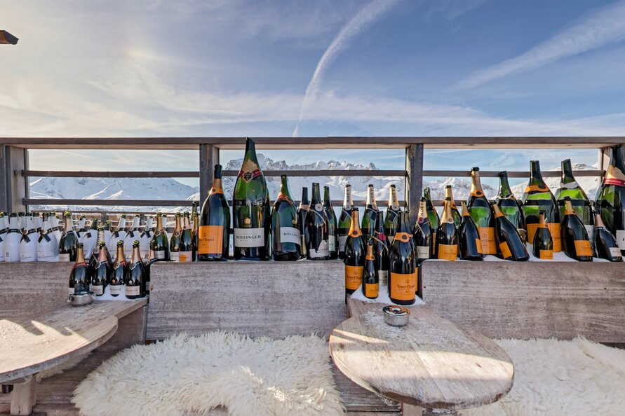 Numerous champagne bottles on a terrace at Balmalp with mountain views.