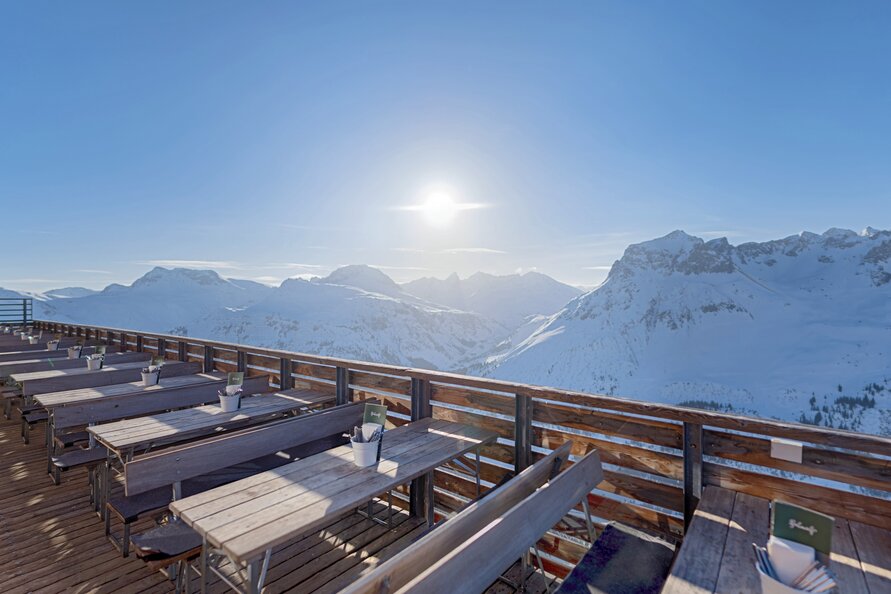Empty Balmalp terrace with tables, mountains, and sunshine.