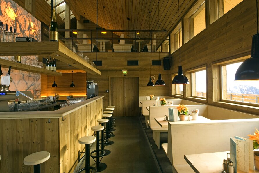Interior view of the cozy, wood-paneled Balmalp restaurant with booths and a bar.