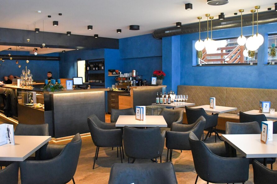 Ein modernes, gemütliches Bistro mit blauen Wänden und eleganter Einrichtung.