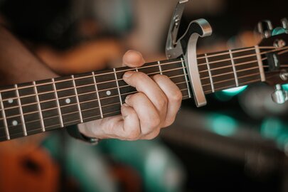 Close-up of a hand playing guitar with a capo.