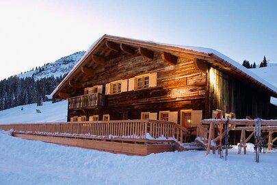 Schneebedeckte Skihütte "Rud Alpe" bei Sonnenuntergang.