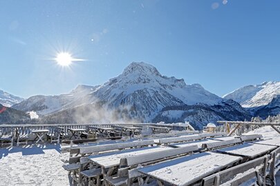Die Sonne bescheint schneebedeckte Tische und Bänke der Rud Alpe-Terrasse.