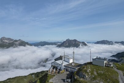 Mountain top Rüfikopf restaurant amid a sea of clouds in the background.