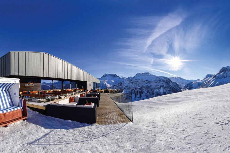 Schlegelkopf Restaurant und verschneite Berge bei Kaiserwetter im Weitwinkel.