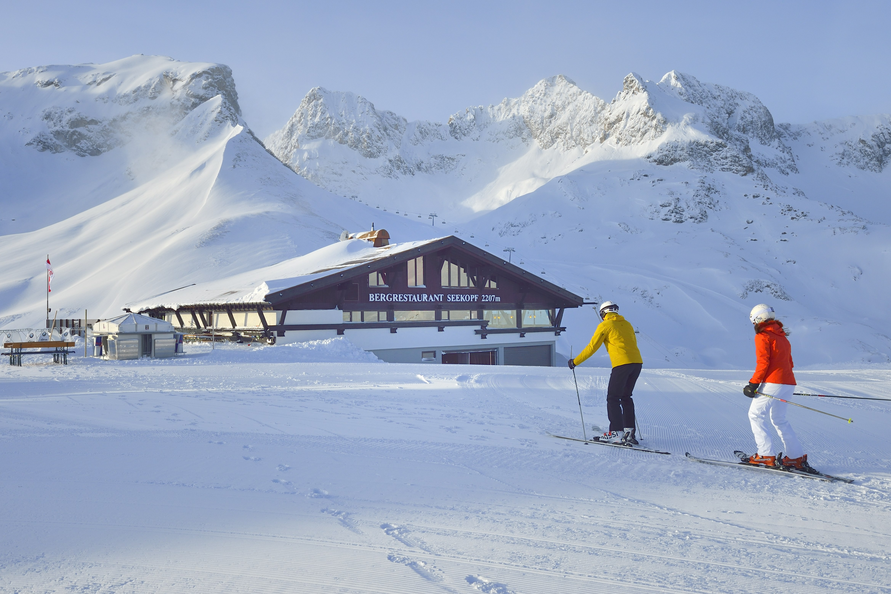 Zwei Skifahrer steuern auf das Seekopf Restaurant zu.