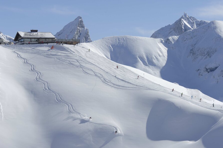 Das Seekopf Restaurant vor schneebedeckten Bergen und Skipisten.