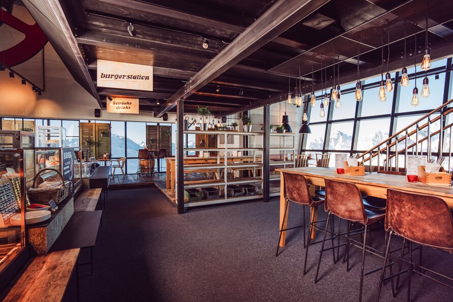 Innenansicht der Trittkopf BBQ Station mit modernen Sitzgelegenheiten und Blick auf die Alpen.