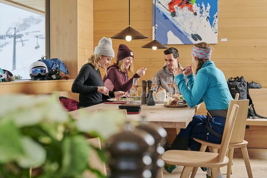 Vier Freunde genießen nach dem Skifahren das Essen im Restaurant Der Wolf.