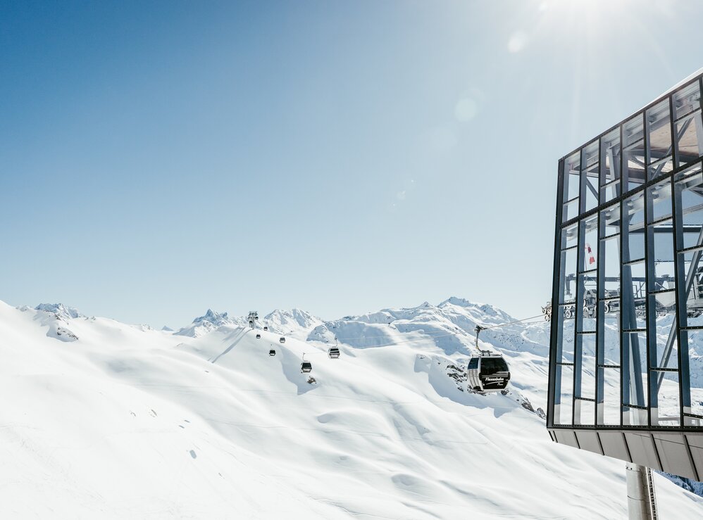 Skilift vor schneebedeckten Bergen und blauem Himmel.