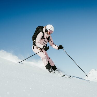 Woman in pink ski gear skiing at Ski Arlberg ski resort.