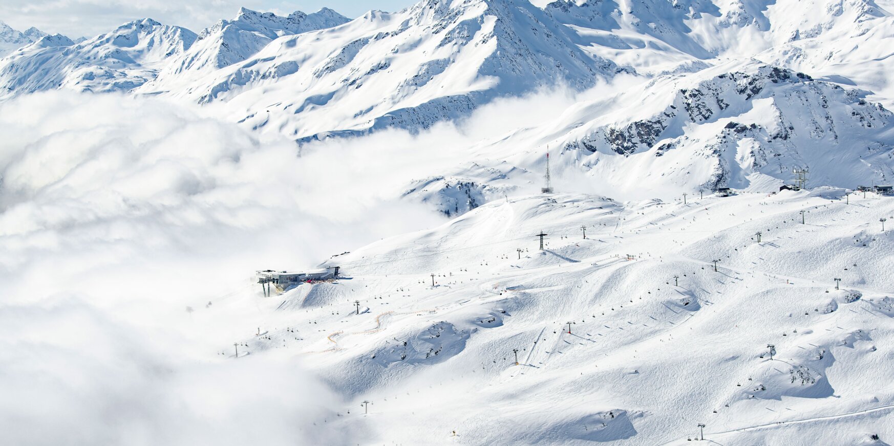 Snow-covered mountains and ski slopes at Ski Arlberg under a blue sky.