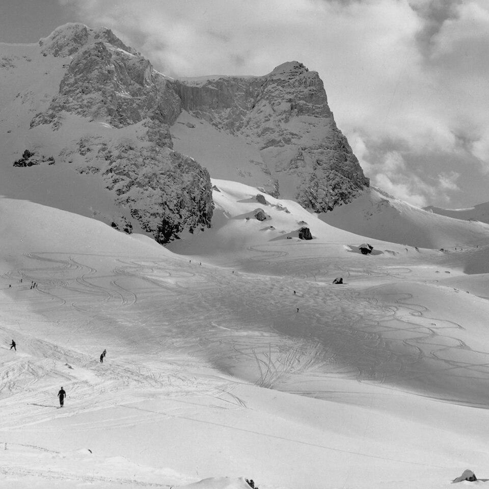 Skiers enjoy fresh powder on a snowy mountain slope.
