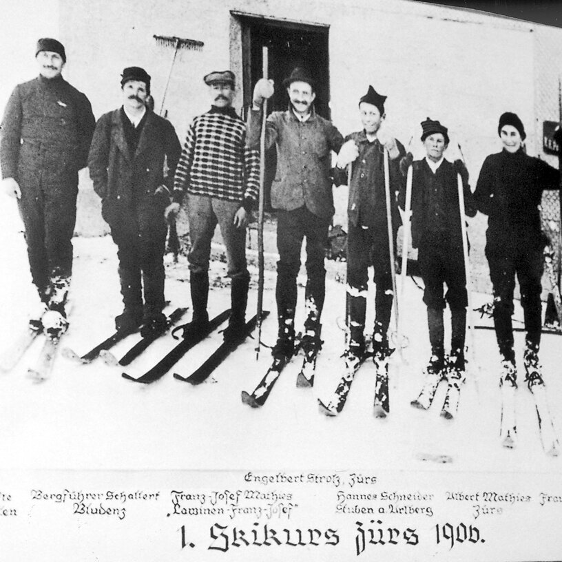 Historic ski course group from 1900 in front of a building.