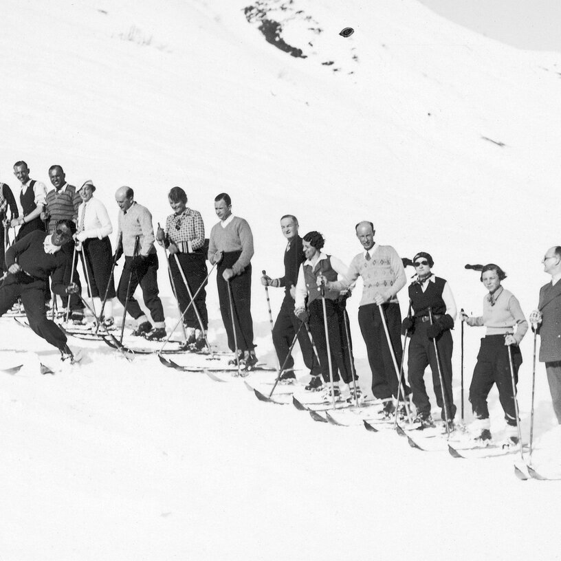 A historic shot of a group of men skiing on a slope.
