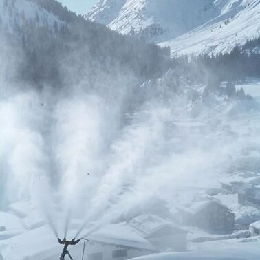 Snow cannon producing snow in a winter mountain landscape.