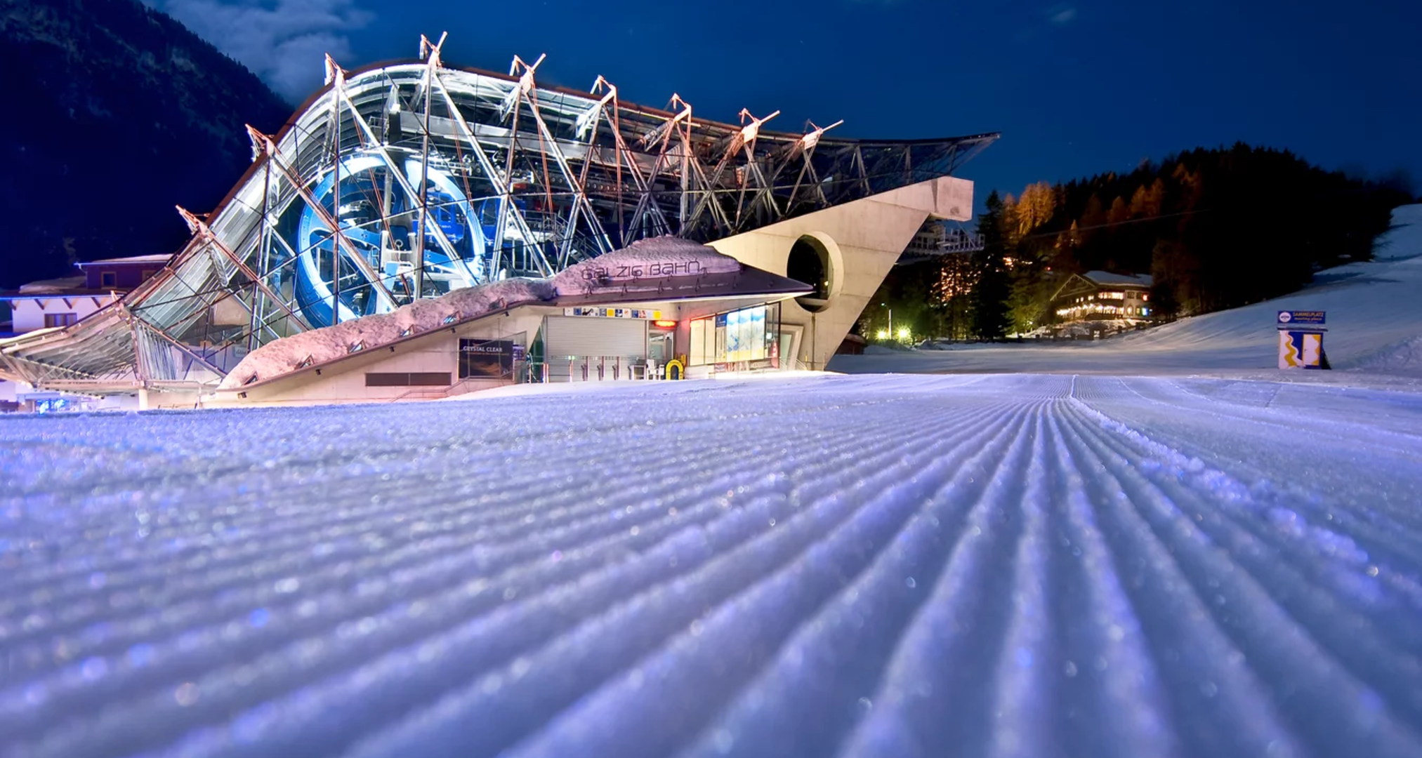 Modern cable car station illuminated at night in snowy landscape.