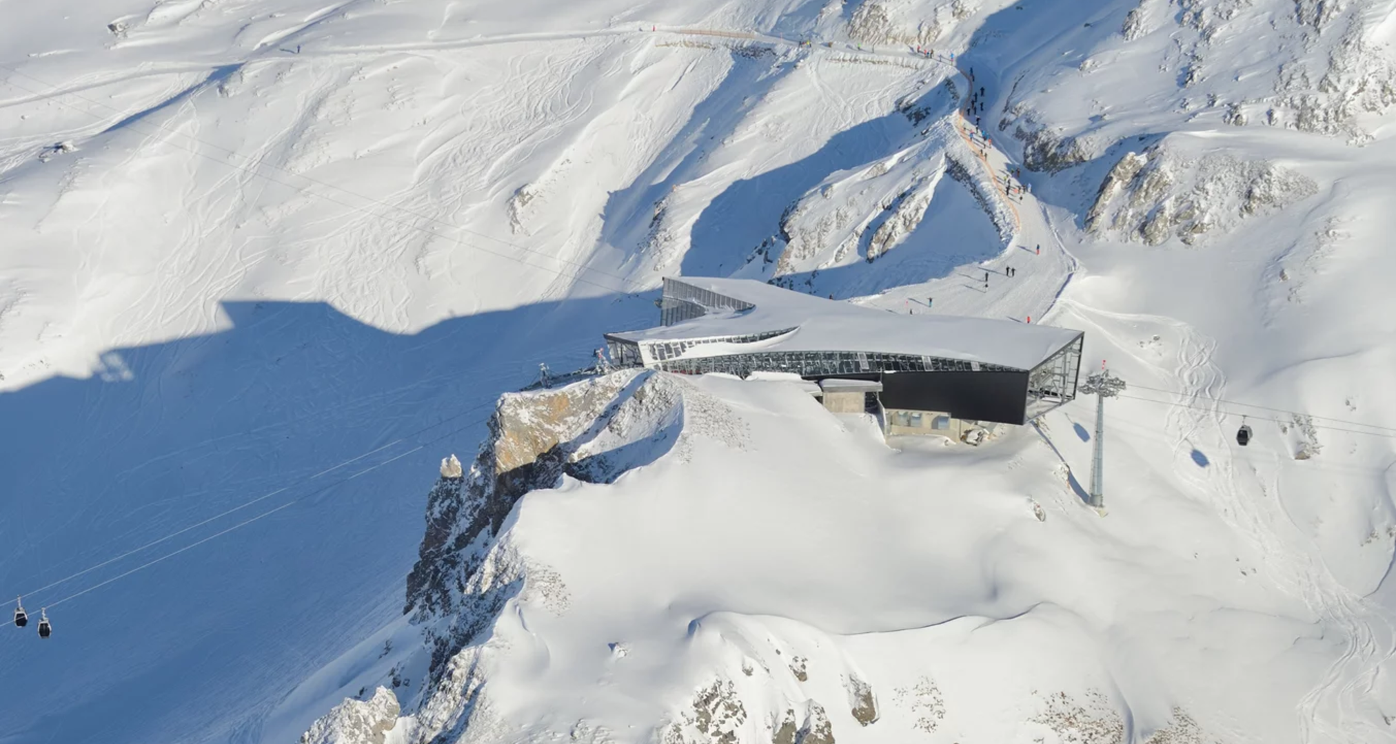 Modern cable car station on a snow-covered mountain peak in winter.