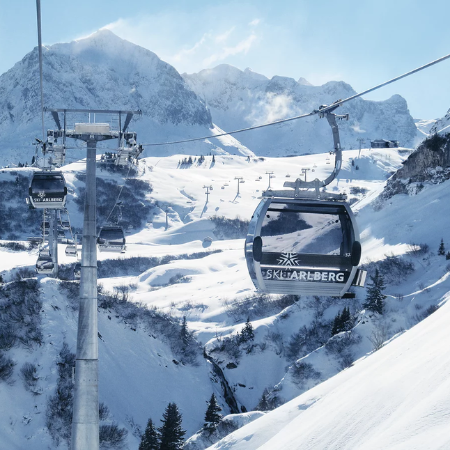 Ski gondolas over snowy landscape with high mountains.