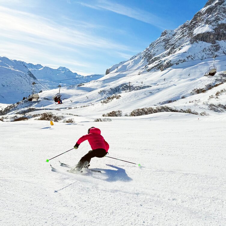 Skier enjoying spring skiing with mountain backdrop.