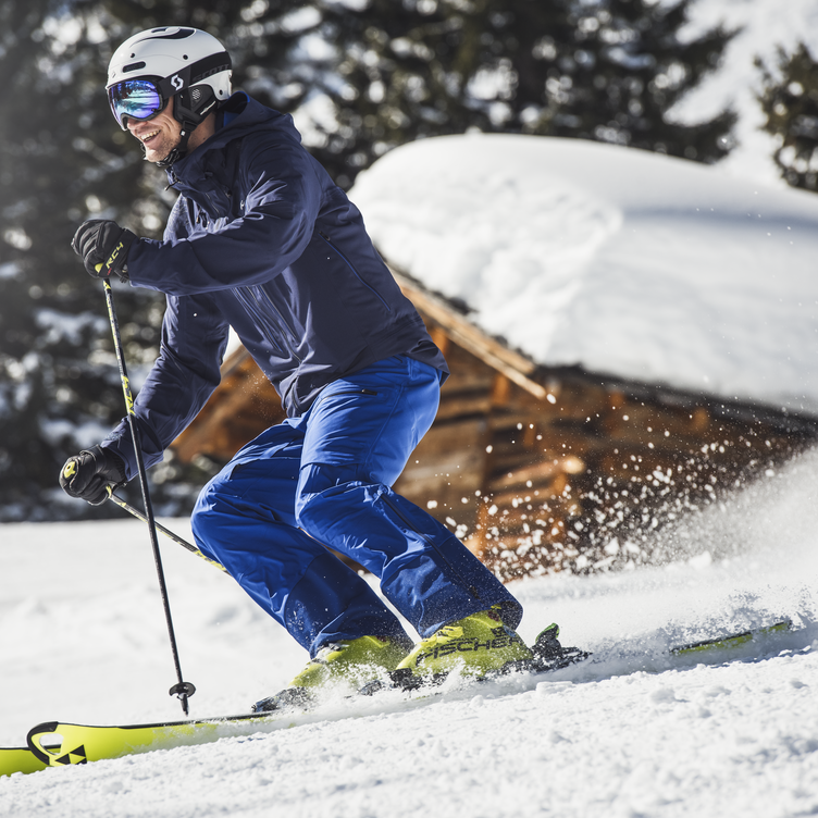 Man in blue ski outfit speeding down snowy slope.