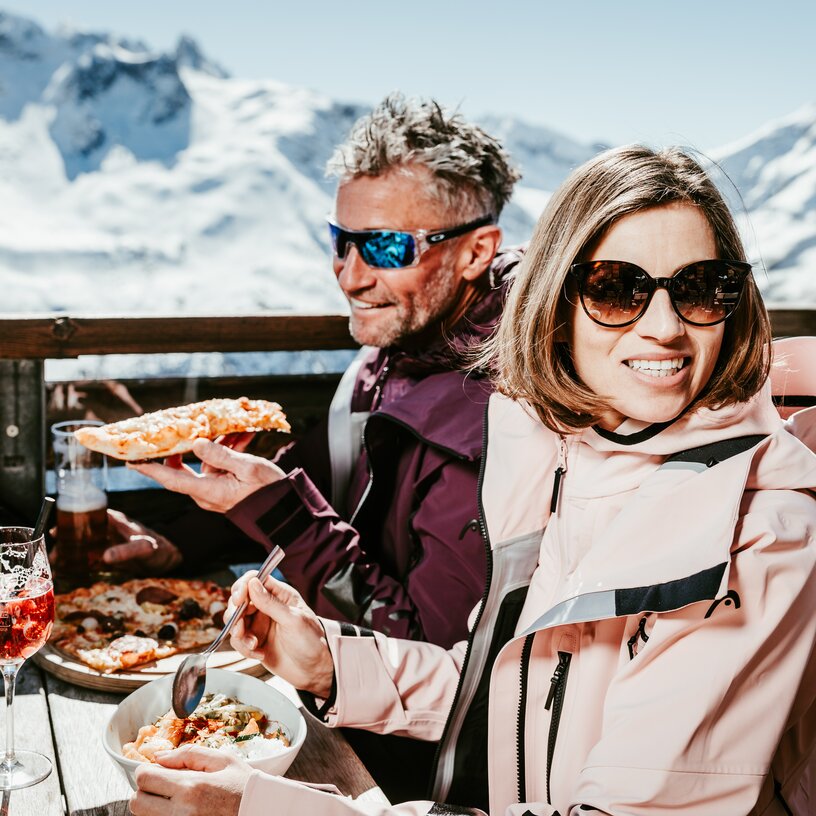 Couple enjoying food and drinks in the snowy Alps.