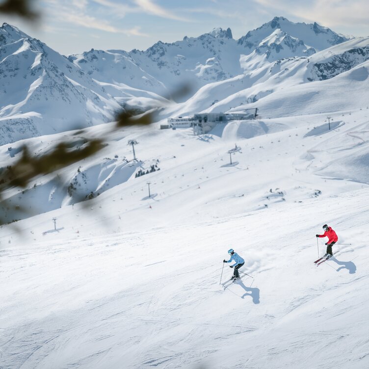 Two skiers descending a snowy slope.