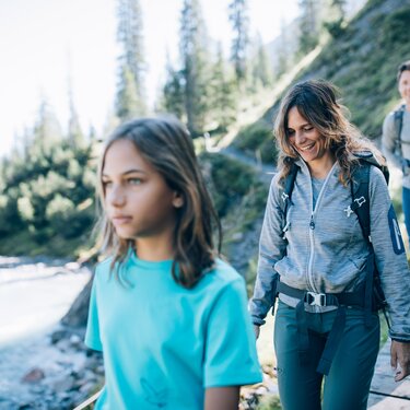 Familie wandert über ein Holzbrücke an einem schönen Sommertag.