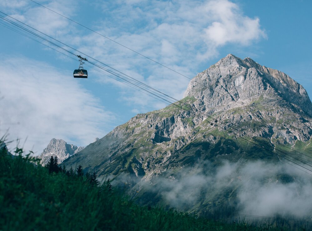 Seilbahn gleitet vor majestätischem Berg und blauem Himmel.