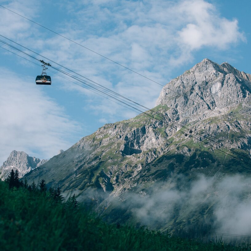 Cable car gliding past majestic mountain and blue sky.