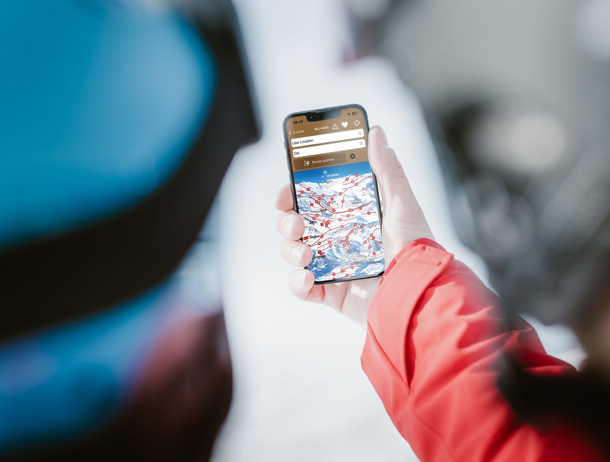 Person in red jacket viewing a ski map on their phone.