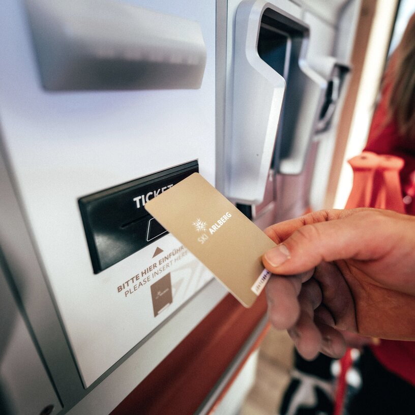 Person buying a ticket at a kiosk with a ski card.
