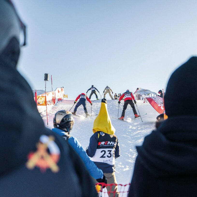 Teilnehmer eines Skirennens in Startposition auf einer Piste.